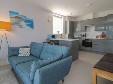 An open living area with a blue sofa and kitchen with grey cabinets at 7 Warren Edge Close in Bournemouth