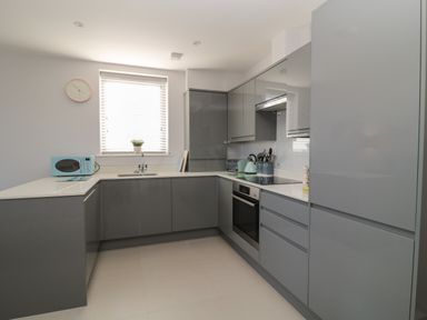 A kitchen with gray cabinets a blue microwave and a window with blinds at 7 Warren Edge Close in Bournemouth