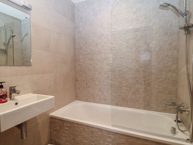 A bathroom with a bathtub shower combination and a sink with a mirror above at 7 Warren Edge Close in Bournemouth