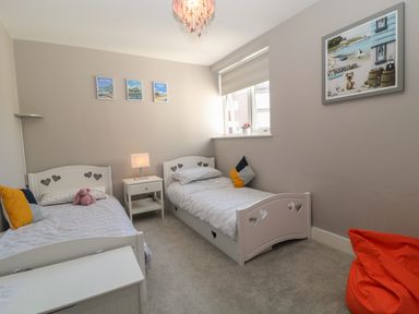 A bedroom with two white beds having heart cutouts and a bedside table with a lamp at 7 Warren Edge Close in Bournemouth