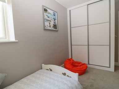 A small bedroom with a single bed a red bean bag and a wardrobe with sliding doors at 7 Warren Edge Close in Bournemouth