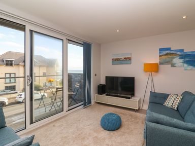 A living room with sliding glass doors leading to a balcony with a table and chairs at 7 Warren Edge Close in Bournemouth