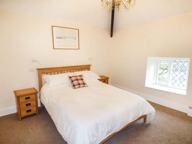 A bedroom with a wooden bed and two wooden bedside tables at Beaver Grove Cottage in Betws-Y-Coed