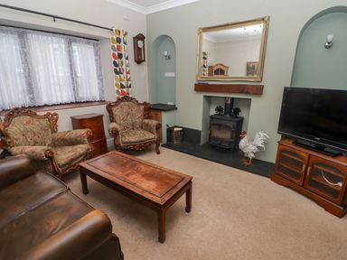 A living room with armchairs a coffee table a television and a fireplace at Cheriton in Pembroke Dock