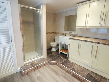 A bathroom with a shower, toilet, sink, and cabinets at Cheriton in Pembroke Dock