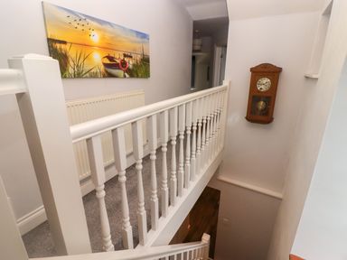 A staircase with white railing a wall clock and a painting above a radiator at Cheriton in Pembroke Dock