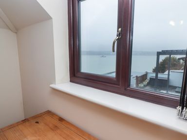 A wooden table next to a window with a view of water and a boat at Cheriton in Pembroke Dock