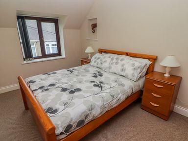 A bedroom with a wooden double bed and two bedside tables with lamps at Cheriton in Pembroke Dock