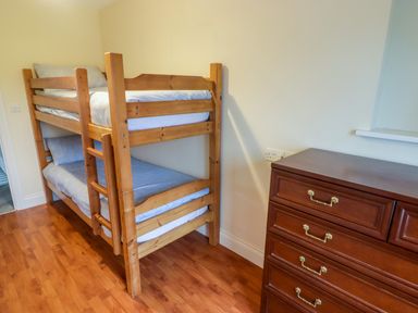 A wooden bunk bed with blue bedding and a brown chest of drawers in a room at Cheriton in Pembroke Dock