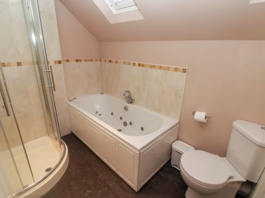 A bathroom with a corner shower, bathtub, toilet, and a skylight window at Cheriton Pembroke Dock
