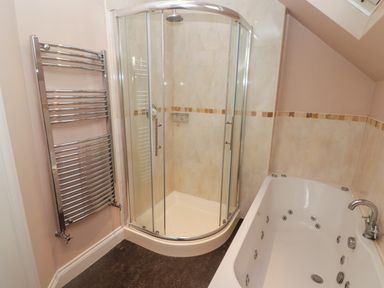 A bathroom with a glass shower enclosure a white bathtub and a wall-mounted towel radiator at Cheriton in Pembroke Dock