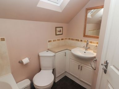 A bathroom with a toilet sink cabinets mirror and skylight at Cheriton in Pembroke Dock