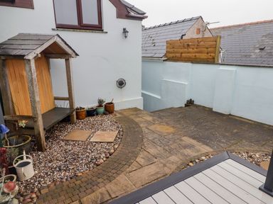 A small backyard area with pebble and brick ground covering and a wooden shelter at Cheriton in Pembroke Dock