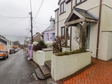 A street with houses on a hill overlooking water at Cheriton in Pembroke Dock