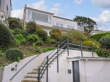 A house on a hill with stairs and bushes at Waves Edge in Looe