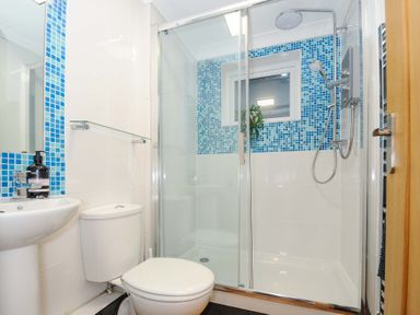 A bathroom with a toilet sink and glass shower at Waves Edge in Looe