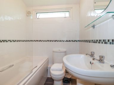 A bathroom with a bathtub toilet sink and a small window at Fox Cove near St Merryn