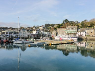 A harbor with boats docked and buildings along the waterfront at Pepper Cove near St Merryn