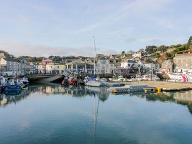 A harbor with boats docked and buildings along the waterfront at Pepper Cove near St Merryn