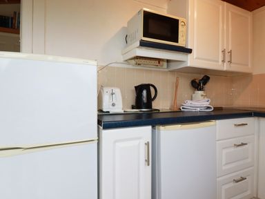 A kitchen corner with a microwave on a shelf a toaster a kettle and utensils in jars on a countertop near Hawker's Cove near St Merryn