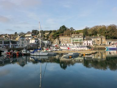 A harbor with boats docked and buildings along the waterfront at Hawker's Cove near St Merryn