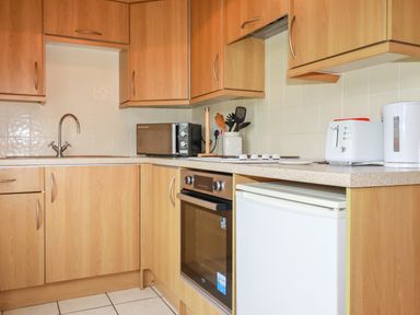 A kitchen with wooden cabinets a sink microwave oven toaster and kettle at Newtrain Bay near St Merryn