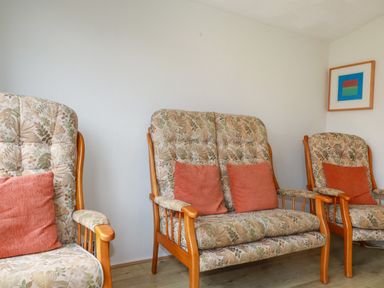 A sitting area with floral upholstered wooden chairs and a framed abstract artwork on the wall at Constantine Bay near St Merryn