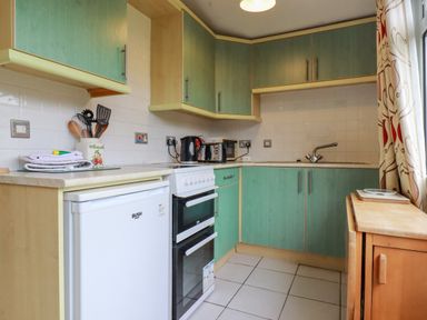 A kitchen with green cabinets white appliances and cooking utensils at Constantine Bay near St Merryn