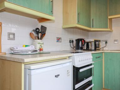 A kitchen with a stove fridge microwave toaster kettle and kitchen utensils at Constantine Bay near St Merryn