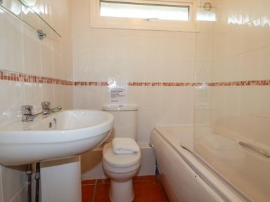 A bathroom with a sink toilet and bathtub with tiled walls at Constantine Bay near St Merryn