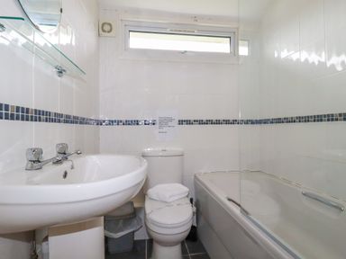 A bathroom with a sink toilet bathtub and a window at Porthcothan Bay in St Merryn