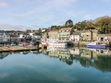 A harbor with several boats docked and buildings along the waterfront at Porthcothan Bay in St Merryn