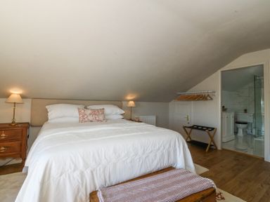 A bedroom with a bed lamps nightstands open clothes rack and an ensuite bathroom at Holly Cottage in Llechwedd near Conwy