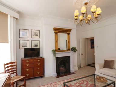 A living room with a fireplace mirror television chest of drawers chair and sofa at Flat 1 in Scarborough