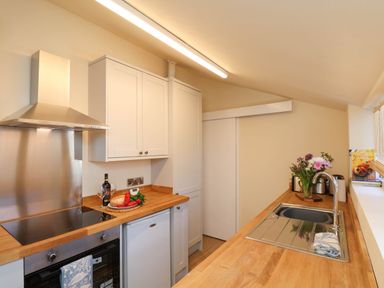 A kitchen with wooden countertops a stove a sink and flowers on the counter at Flat 1 in Scarborough