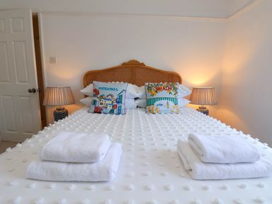 A bedroom with a bed with textured white bedspread and two decorative pillows each side with lamps at Flat 1 in Scarborough