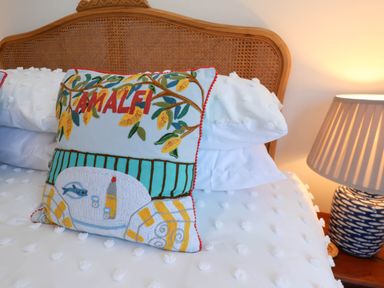A bed with a decorative Amalfi pillow white bedding and a table lamp at Flat 1 in Scarborough