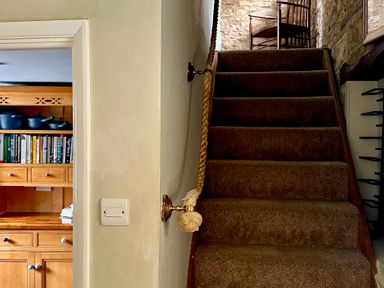 A staircase with an open doorway leading to a kitchen at Lamorna Cottage in Chipping Norton