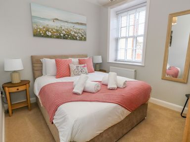 A bedroom with a bed pink throw pillows and a pink blanket on the bed at Two @ No36 in Weymouth