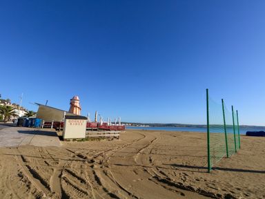 A sandy beach with a donkey rides sign and a helter skelter near a calm sea at The Loft @ No36 in Weymouth