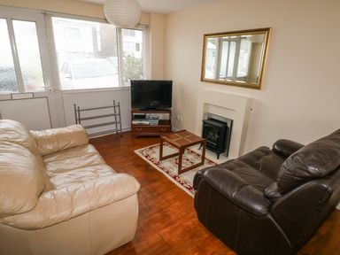A living room with two sofas a small table a television on a stand a fireplace and a large mirror at Freshwater East in Freshwater East