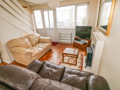 A living room with two sofas a small wooden table a television and a wall mirror at Freshwater East in Freshwater East