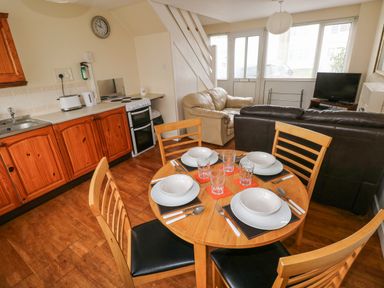 A kitchen and living area with wooden dining table set for four and sofas at Freshwater East in Freshwater East