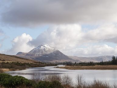 A river flowing through a plain with a snow capped mountain and cloudy sky at Nelly's House in Gortahork County Donegal