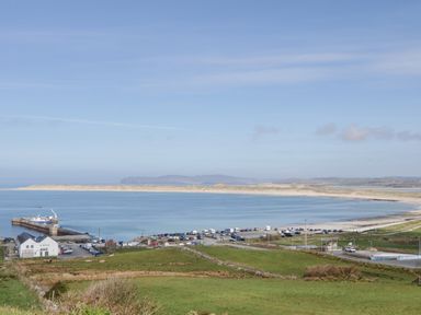 A coastal area with a bay a pier vehicles on land and grassy fields at Nelly's House in Gortahork County Donegal