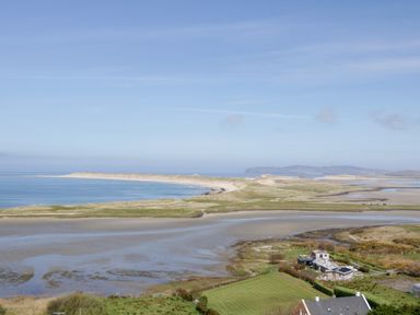 A coastal landscape with sand dunes water and houses at Nelly's House in Gortahork County Donegal