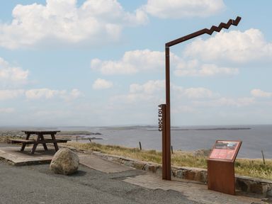 A picnic table and an informational sign along a coastal path with ocean and islands in the background at Nellys House in Gortahork County Donegal