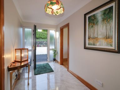 A hallway with a side table and lamp a green mat and a framed painting at Nelly's House in Gortahork County Donegal