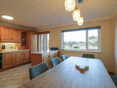 A kitchen and dining area with wooden cabinets, a wooden dining table with chairs and pendant lights above at Nelly's House in Gortahork County Donegal