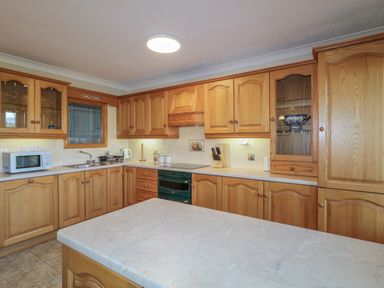 A kitchen with wooden cabinets a microwave oven a sink and a countertop at Nelly's House in Gortahork County Donegal